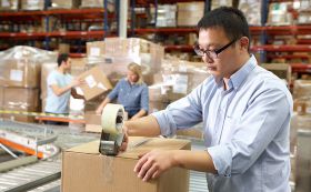 Shipping Clerk taping up boxes for transport.