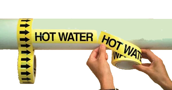 Worker applying yellow tape roll pipe marker for hot water